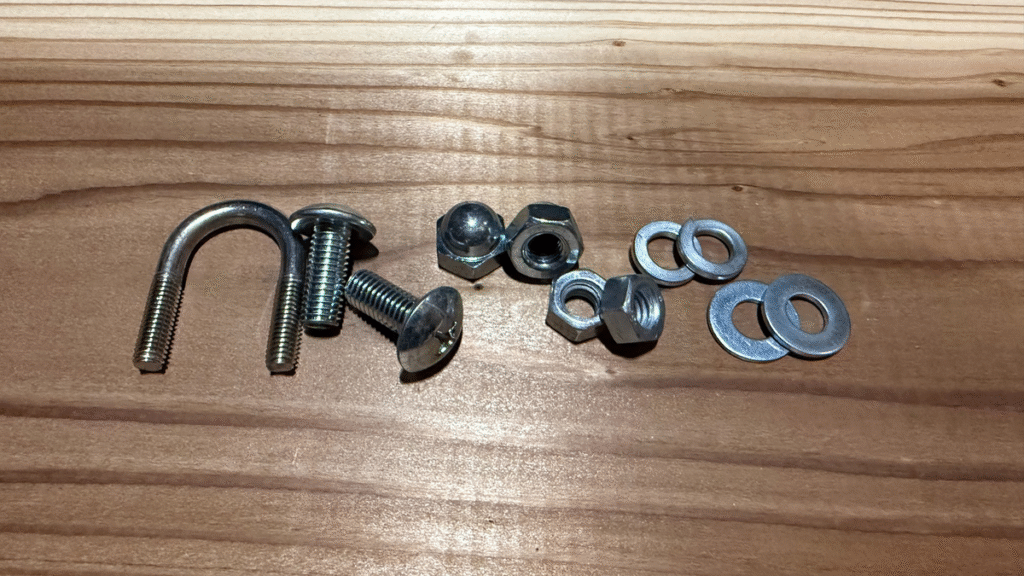 筆者撮影：左からU字ボルト、トラスボルト、袋ナット、六角ナット、スプリングワッシャー、ワッシャーを並べた写真。ボルトとナットの種類比較用。