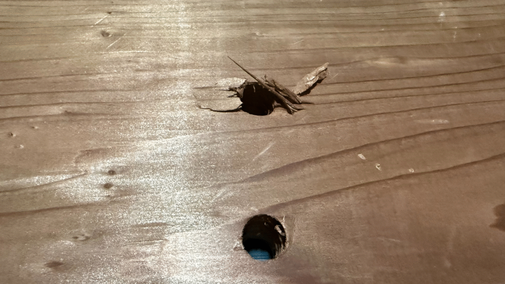 筆者撮影:木材に開けた穴の比較写真。上は一気に貫通させて裏面がささくれた例、下は上下から開けて仕上がりがきれいな例を示している。