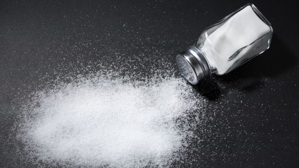 食卓塩の瓶が倒れて塩がこぼれている画像